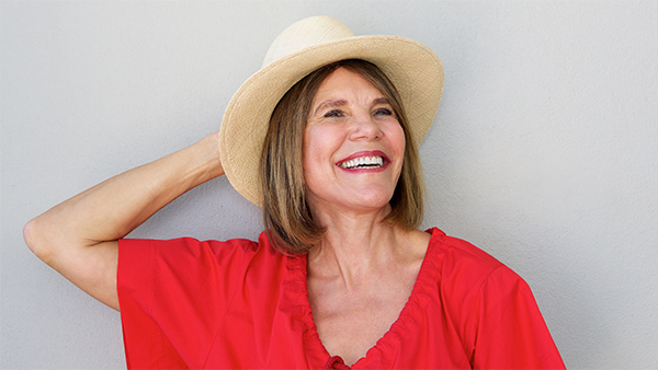 Happy middle aged woman wearing red t-shirt and straw hat